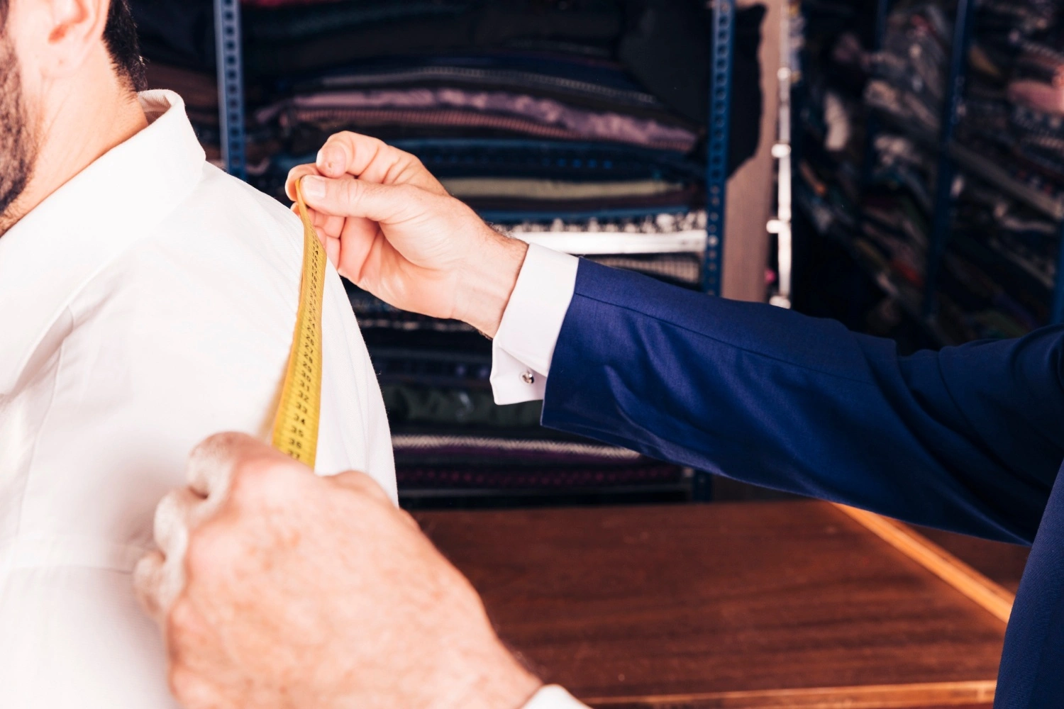 A professional tailor adjusting the fit of a men's garment, ensuring precision and style with FCOM India’s specialized tailoring services